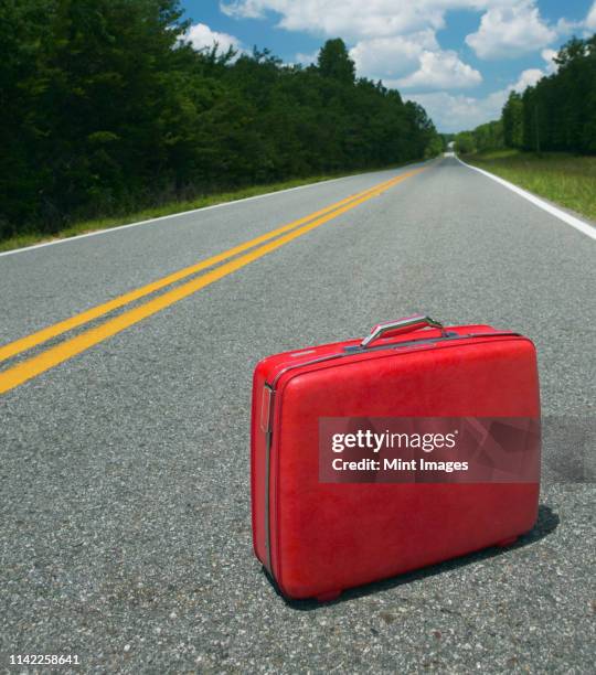 red suitcase abandoned in road - abandoned stock pictures, royalty-free photos & images