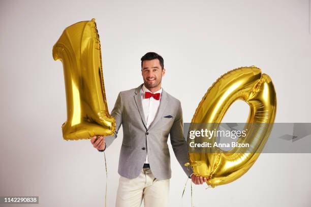 young man with golden balloon building the figure "10”. debica, poland - ten of clubs stock-fotos und bilder