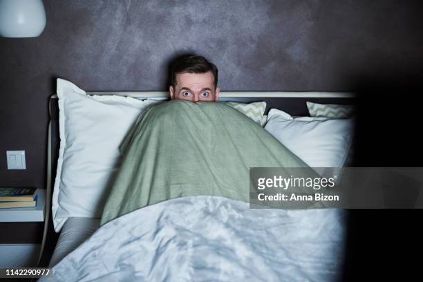 scared man watching horror movies in bed. debica, poland - solo 2018 film foto e immagini stock