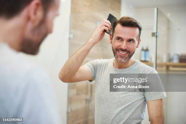 man combing his hair in the bathroom. debica, poland - man combing hair stock pictures, royalty-free photos & images