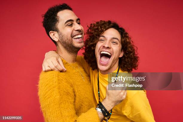 colourful studio portrait of a gay male couple - rire aux éclats photos et images de collection