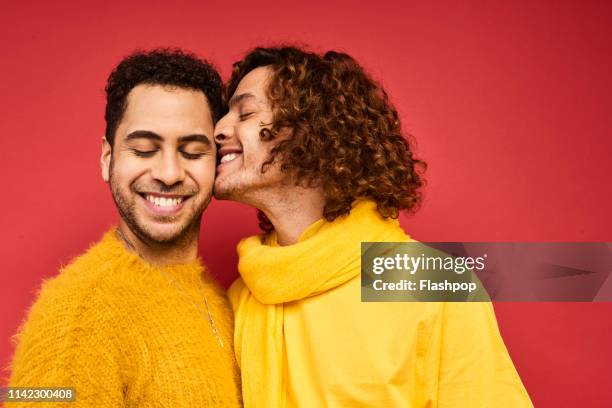 colourful studio portrait of a gay male couple - kissing photos stockfoto's en -beelden