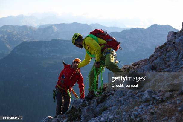 helpieren in den bergen - bergsteiger stock-fotos und bilder