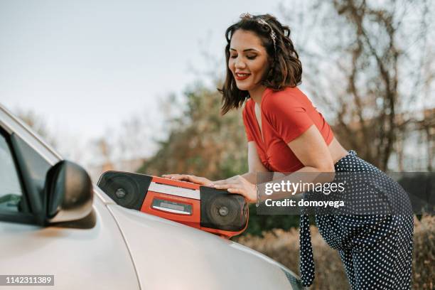pin-up girl listening to music from a radio in the city street - lady relaxing in sun radio stock pictures, royalty-free photos & images