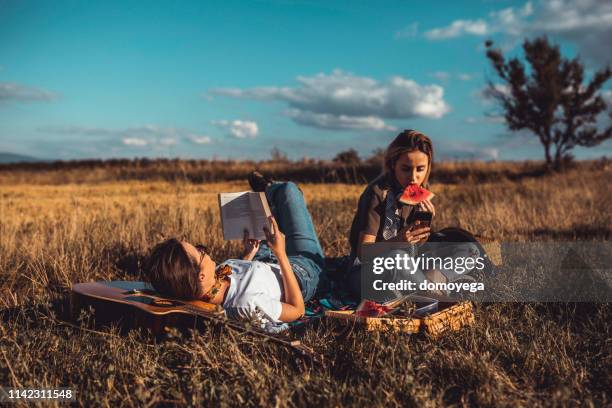 schöne zwillingsschwestern, die ein picknick machen und wassermelone essen - love books stock-fotos und bilder