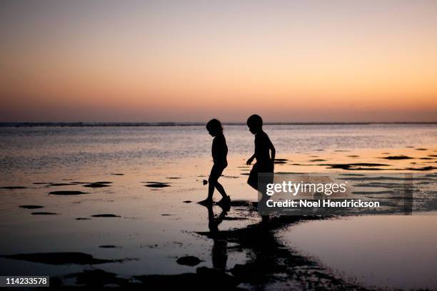 2 children walking next to the beach at sunset - child silhouette ocean stock pictures, royalty-free photos & images