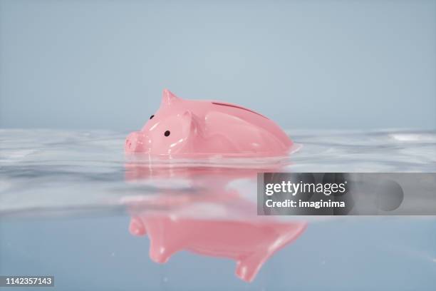 zinkende piggy bank - recessie stockfoto's en -beelden