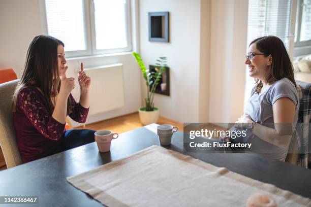 twee vrolijke dove vrouwen praten met gebarentaal - pregnancy class stockfoto's en -beelden