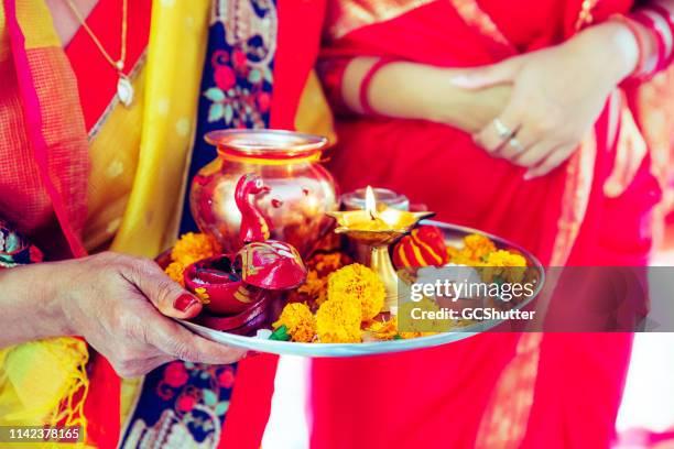 mujer mayor sosteniendo artículos de oración hindú en una bandeja - ganesh chaturthi fotografías e imágenes de stock