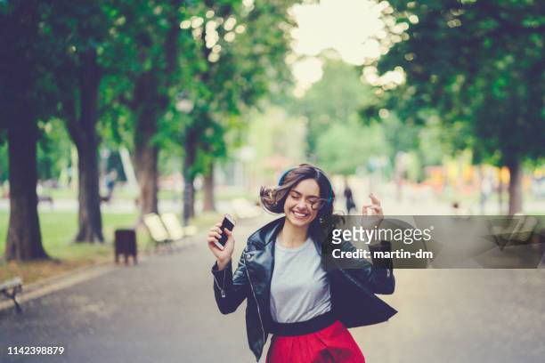 gelukkig meisje genieten van een goede muziek in het park - girl swing stockfoto's en -beelden