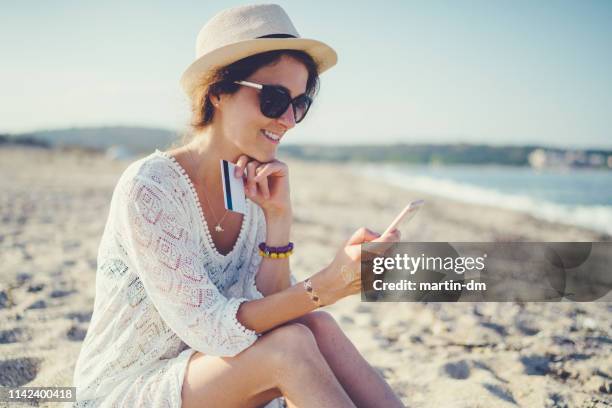 tourist at the beach making online payments with credit card - travel budget stock pictures, royalty-free photos & images