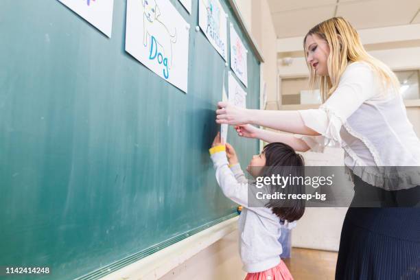 child learning english language while playing games in classroom - japanese people lesson english stock pictures, royalty-free photos & images