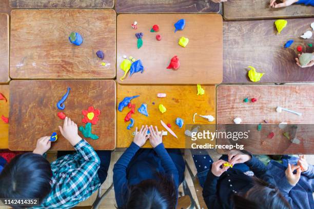 kinderen spelen met klei in de klas - klei stockfoto's en -beelden