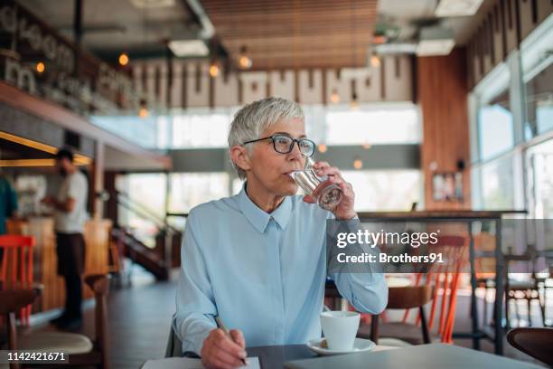 woman drinking water - mature women cafe stock pictures, royalty-free photos & images