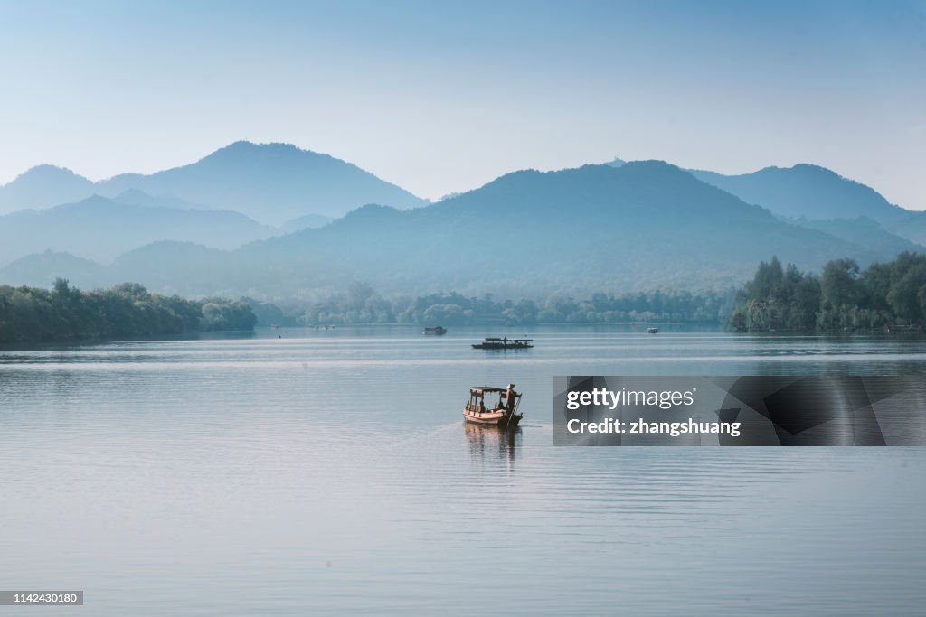 Silhouetted fishing boat on West lake, Hangzhou, China