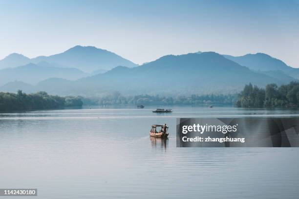 silhouetted fishing boat on west lake, hangzhou, china - hangzhou stock pictures, royalty-free photos & images