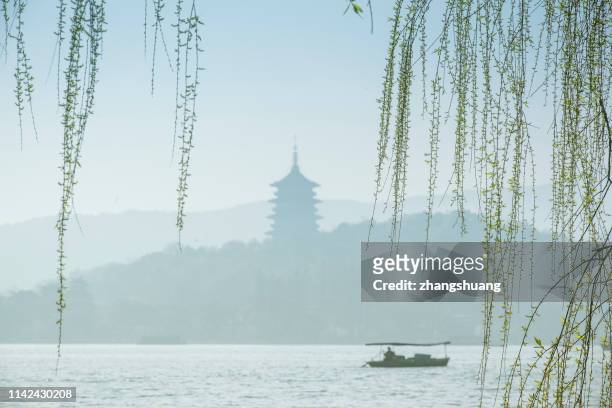 silhouetted fishing boat on west lake, hangzhou, china - west lake hangzhou stock pictures, royalty-free photos & images