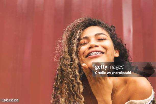 portrait of a brazilian girl smiling with eyes closed - free orthodontic braces stock pictures, royalty-free photos & images