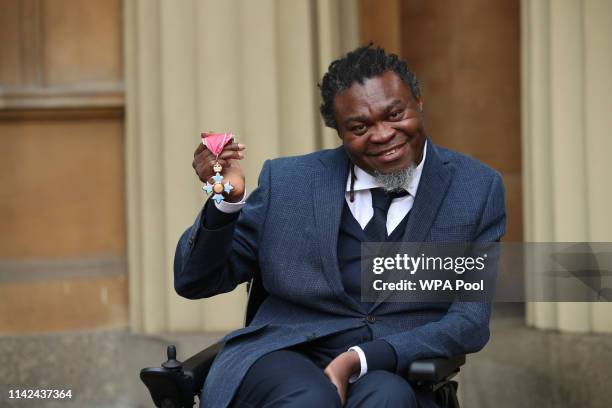 Yinka Shonibare holds his CBE for services to art following an investiture ceremony at Buckingham Palace on May 9, 2019 in London, England.