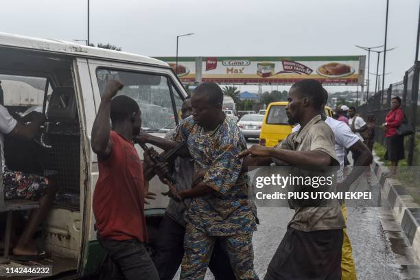 Commuters sit in a bus and watch driver exchange blows with fellow motorist to further compound the chaotic traffic gridlock at Ojota district of...