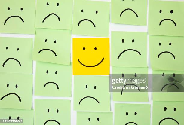 sad faces on sticky notes with one happy one - positive emotion stock pictures, royalty-free photos & images