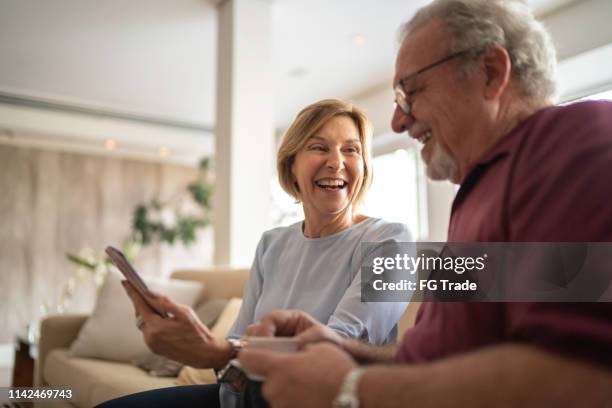 senior couple drinking coffee and using cellphone - good news stock pictures, royalty-free photos & images