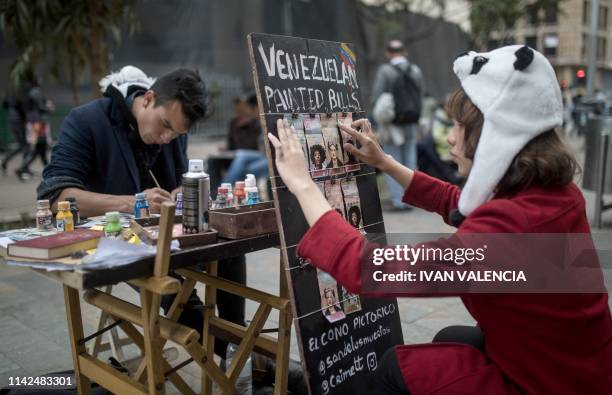 Venezuelan migrants Javier Ceballos and Paula Villamizar, who paint Venezuelan Bolivar bills for a living, work in a street in Bogota, Colombia, on...