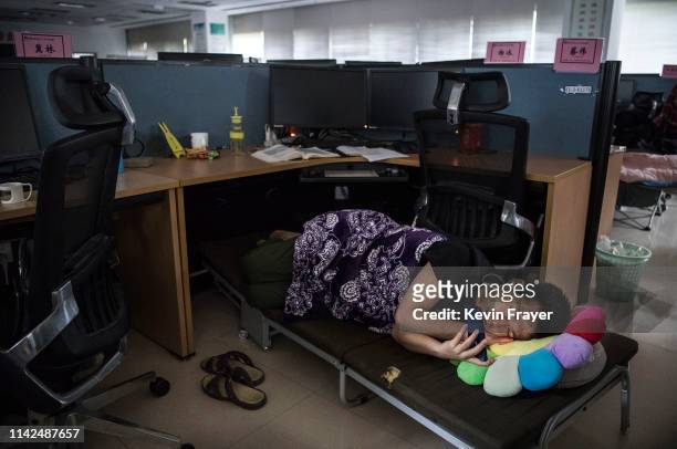 Huawei employee watches a program on his smartphone as he rests at his cubicle during lunch break, which is known to be common practice in many...