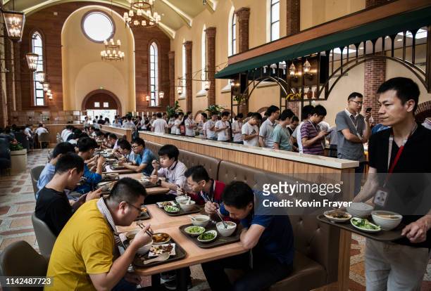 Huawei workers eat lunch as others line-up at one of many cafeterias serving subsidized food at the sprawling 'Ox Horn' Research and Development...