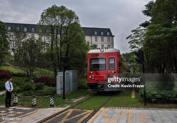 Huawei security guard stands at a crossing as a train used by employees, clients and visitors passes by near the 'Paris Station' of the new sprawling...