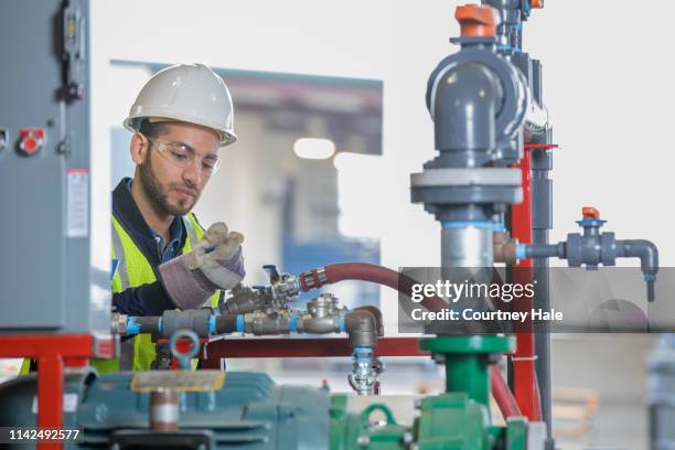 young professional engineer working on equipment at oil and gas industry job site - gas compressor stock pictures, royalty-free photos & images