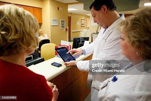 Cardiologist Dr. Jose Soler demonstrates to hospital CEO Dianne Goldenberg, let, and CNO Cathy Philpoh an app on an iPad to review medical tests of...