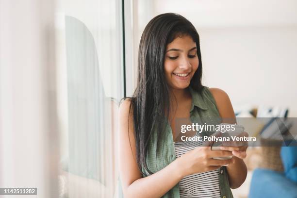 teenage meisje met behulp van cellphone in de buurt venster - very young webcam girls stockfoto's en -beelden