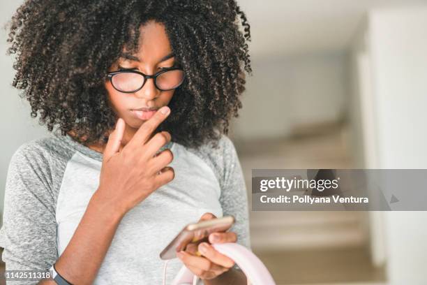 afro teenager-mädchen mit smartphone zu hause - african american girl look up stock-fotos und bilder