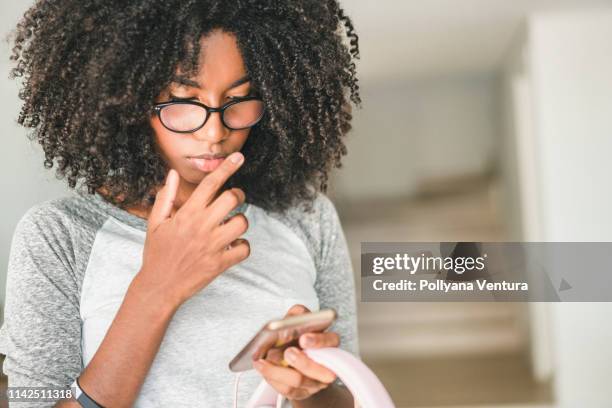 meninas do adolescente do afro que usam o smartphone em casa - erro - fotografias e filmes do acervo
