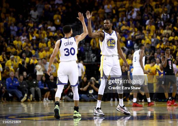 Stephen Curry high fives Kevin Durant of the Golden State Warriors during their game against the LA Clippers during Game One of the first round of...
