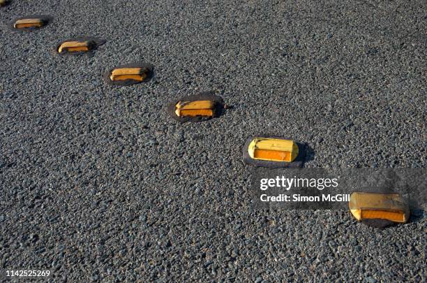 yellow plastic road reflectors on a city street - road reflector stock pictures, royalty-free photos & images