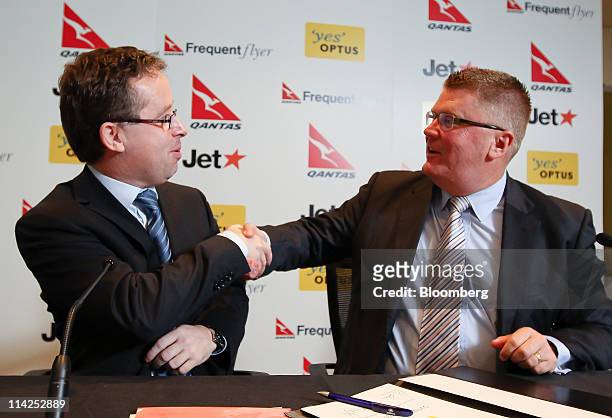 Alan Joyce, chief executive officer of Qantas Airways Ltd., left, shakes hands with Michael Smith, managing director of the consumer division of...
