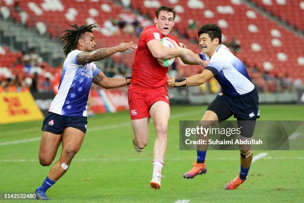 Jake Thiel of Canada is tackled during the Challenge Trophy quarter final between Japan and Canada on day two of the HSBC Rugby Sevens Singapore at...