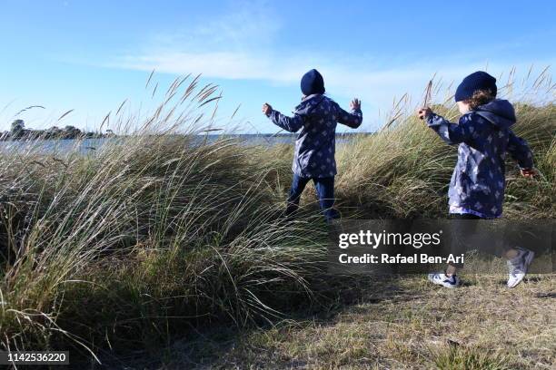 young girls running to the beach - australia winter stock-fotos und bilder