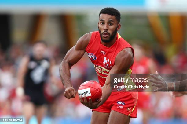 Touk Miller of the Suns handballs during the round four AFL match between the Gold Coast Suns and the Carlton Blues at Metricon Stadium on April 14,...