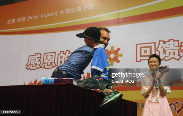 Australian preacher and motivational speaker Nick Vujicic hugs a disabled child during his public lecture at Zhongnan University of Economics and Law...