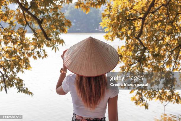 vietnamese woman with asian style conical hat looking at lake during day . - asian style conical hat fotografías e imágenes de stock