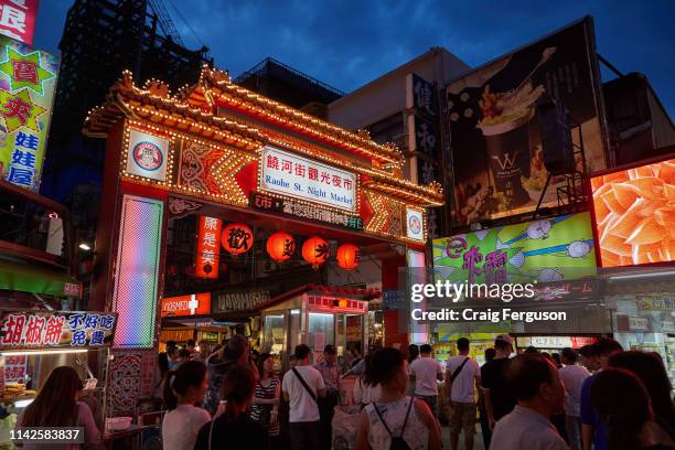 Tourists and locals walk around Raohe night market in the early evening. The market is one of the most popular in Taipei, with a wide variety of...