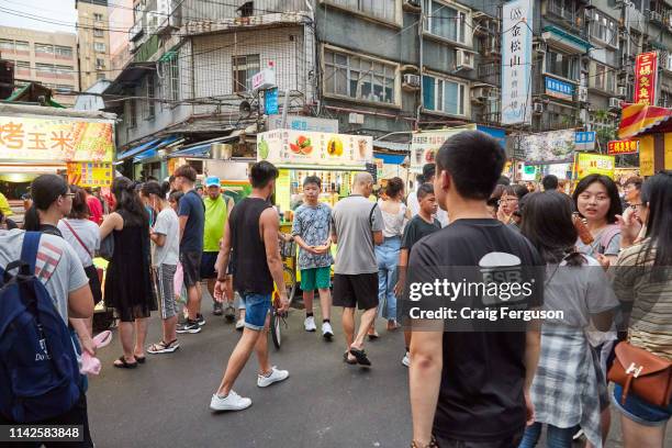 Tourists and locals walk around Raohe night market in the early evening. The market is one of the most popular in Taipei, with a wide variety of...