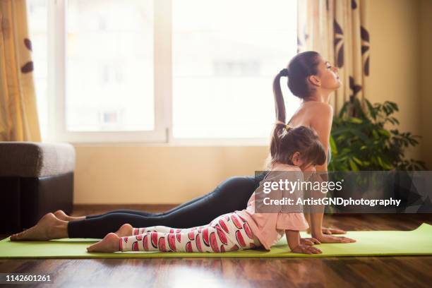 du gör det som mamma nu, full längd skott av en mor och dotter gör yoga tillsammans - daily sport girls bildbanksfoton och bilder