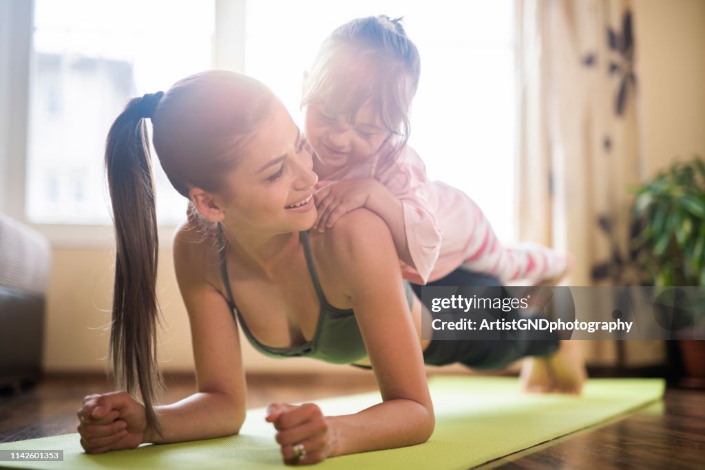 Mittelerwachsene Mutter praktiziert Yoga mit todkranke Tochter auf ihr, schöne Mutter und Tochter Training zu Hause Training Training