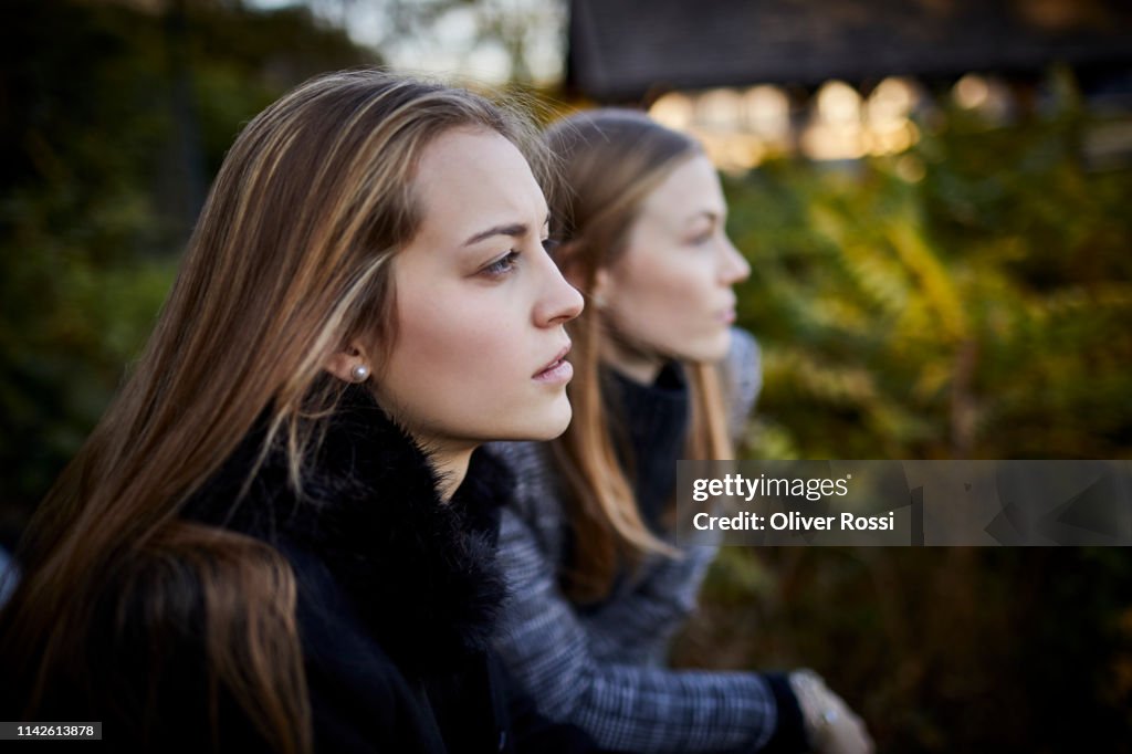 Two young women leaning on railing looking at view