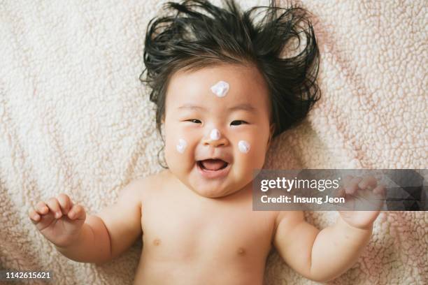 mother rubbing lotion on baby girl (6-11 months) - korean baby girl stock-fotos und bilder