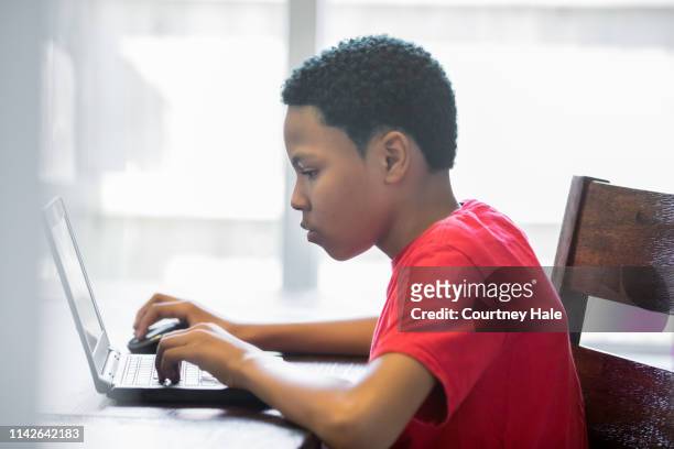 young teenage boy working on homeschool assignments using laptop at home - boys stock pictures, royalty-free photos & images